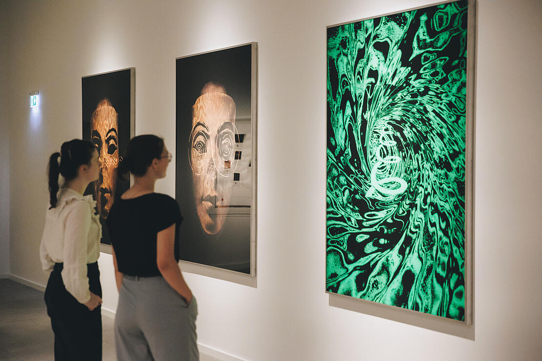 Besucherinnen betrachten ein Werk von Ugo Dossi in der Ausstellung 