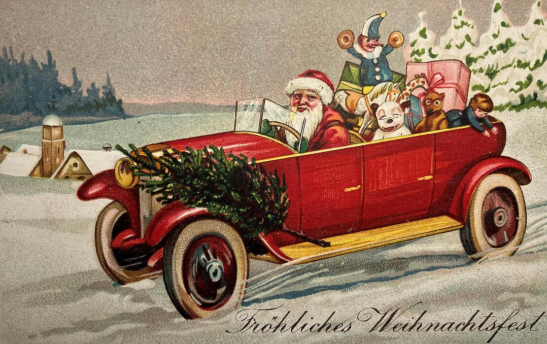 Historische Postkarte: Weihnachtsmann fährt mit einem roten Cabrio durch Schneelandschaft, hinten im Auto sind Geschenke, vorne am Auto ein Tannenbaum