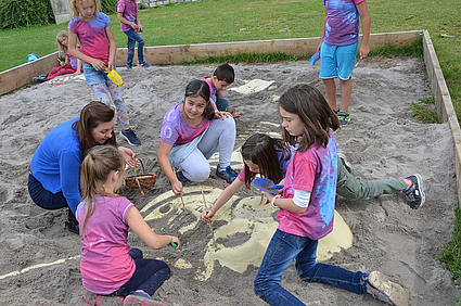 Kinder legen ein unter Sand verstecktes Mammut-Skelett frei. 