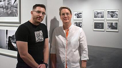 Fotograf Jean-Michel Landon und ZEPHYR-Leiterin Stephanie Herrmann stehen an eine Wand gelehnt in der Foto-Ausstellung „La vie des blocs“ 