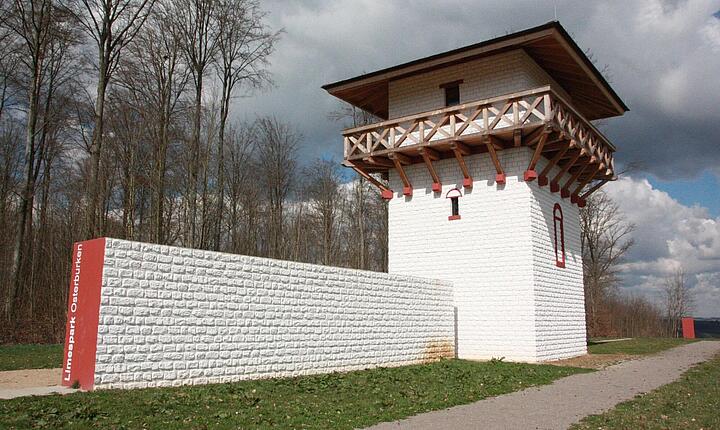 Weißer Turm mit Holzbalkon, daran weiße Mauer Weißer Turm mit Holzbalkon, daran weiße Mauer