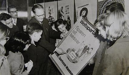 Weltspartag, ca. 1960: Mann zeigt Kindern ein weltspartag-Plakat