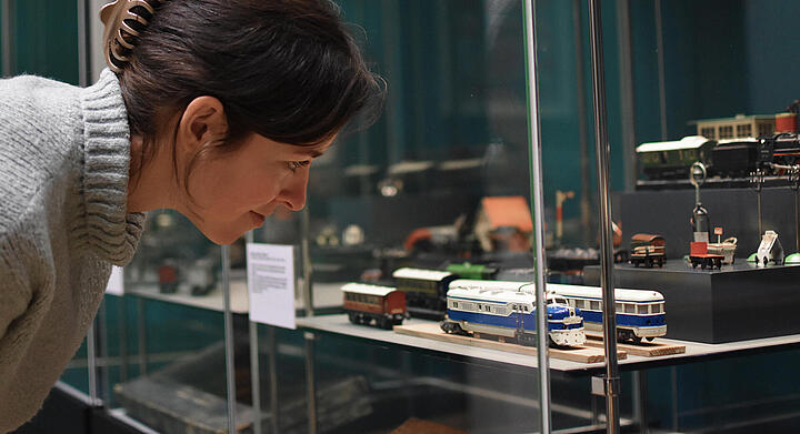 Eine Frau betrachtet in einer Vitrine Modellbahnen Eine Frau betrachtet in einer Vitrine Modellbahnen