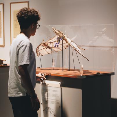Ein Jugendlicher testet in Ausstellungsräumen das Modell eines Flugobjektes.