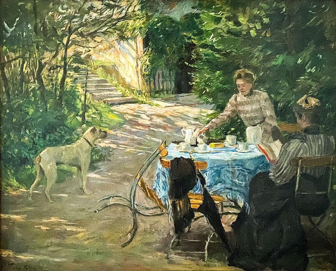 Gemälde zeigt eine gedeckte Kaffeetafel im Freien, eine Frau schenkt Kaffee ein, eine Frau liest in einem Buch, links steht ein Hund