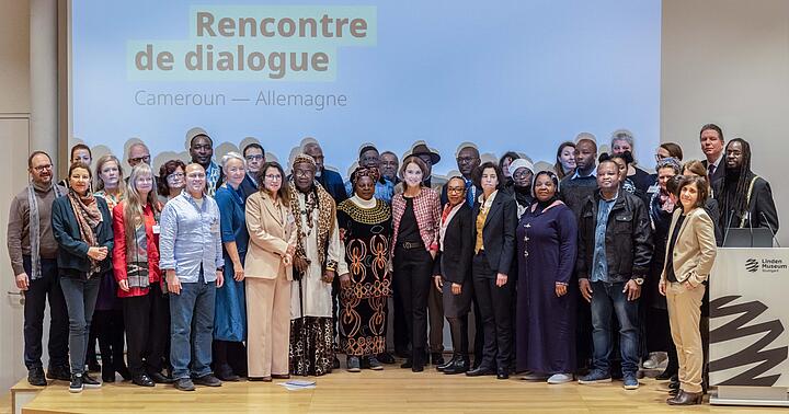 Das Gruppenbild zeigt zahlreiche Menschen aus Kamerun und Deutschland auf einer Bühne