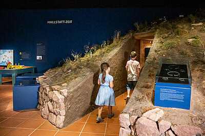Kinder betreten die Rekonstruktion eines Grabhügels in der Ausstellung