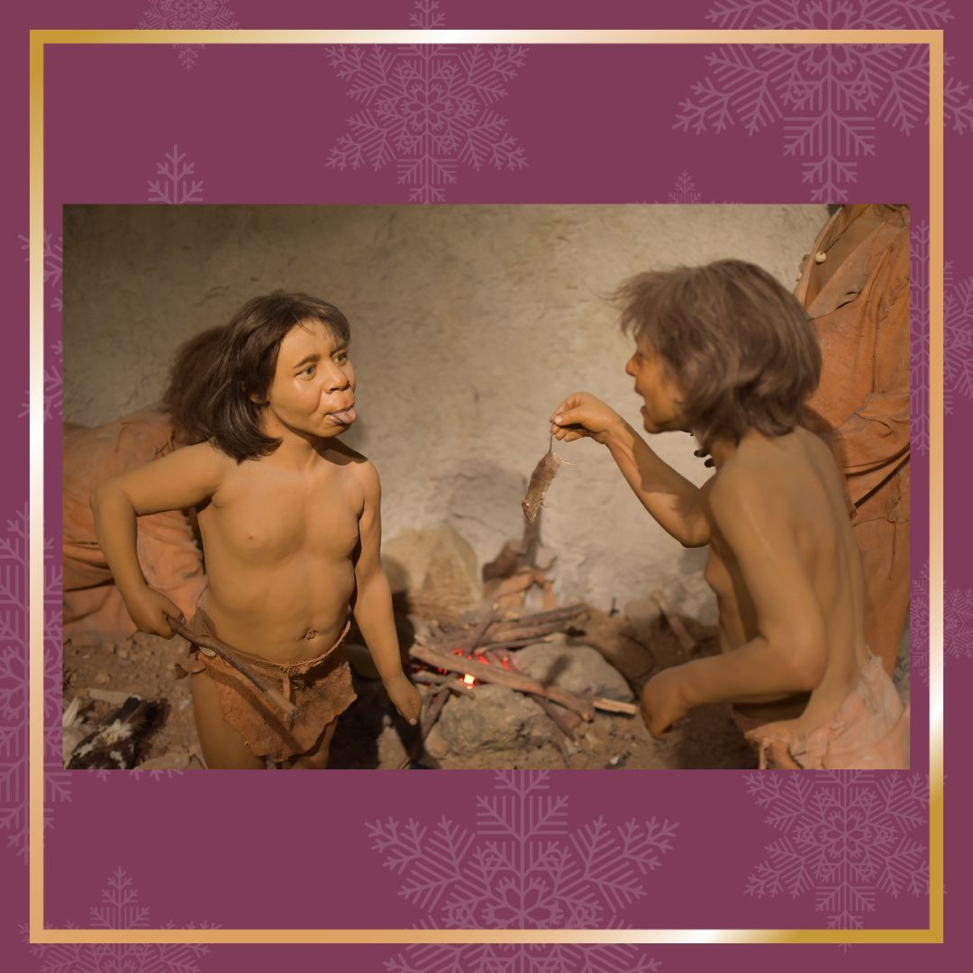 Zwei nachgebildete Kinder in einer Steinzeitszenerie spielen miteinander in einer Höhle